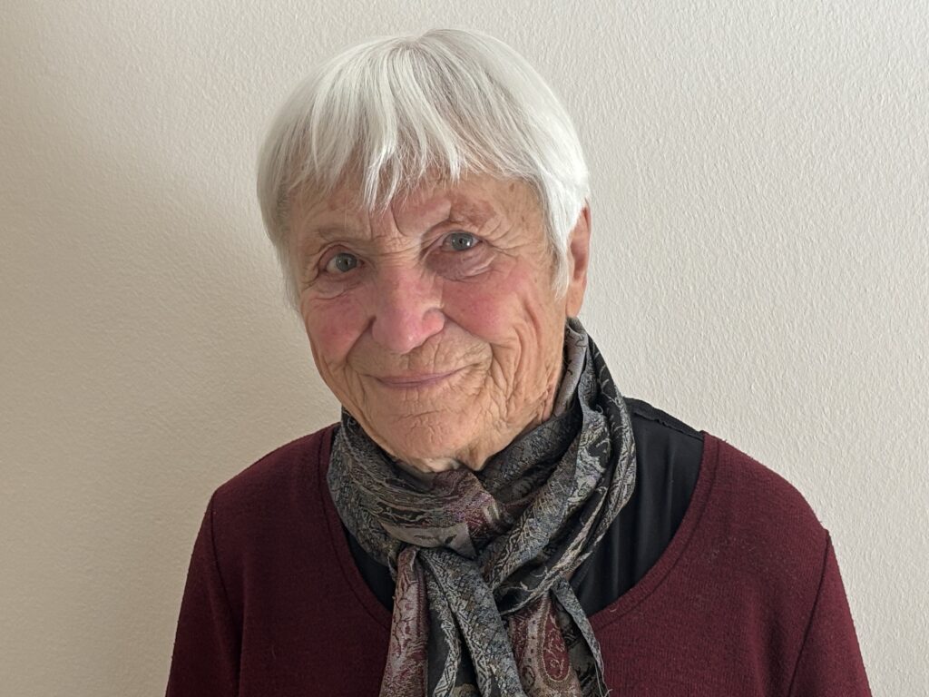 Maike Schmauß in rotem Pullover und Schal lächelt in die Kamera
