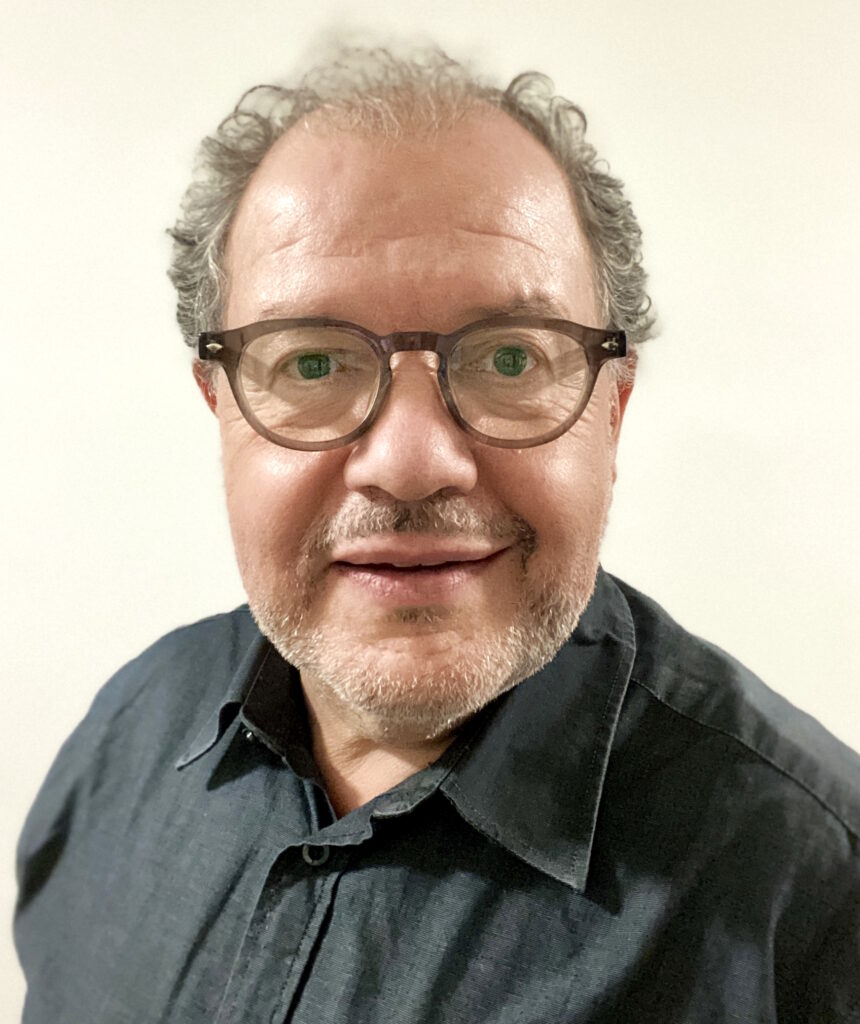 Peter Spiel mit Brille und Hemd lächelt in die Kamera
